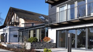 A modern building with large glass windows, a stone facade, and a balcony. - WESTSIDE Hotel Garni (Munich)