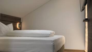 Un dormitorio moderno con tragaluces, una cama y televisor montado en la pared.