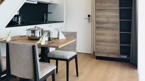 A modern kitchen with a dining area, a staircase, and a view of the living area. - WESTSIDE Hotel Garni (Munich)