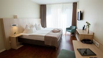 Une chambre d’hôtel comprenant un lit, une table de chevet, une chaise, un bureau et un téléviseur.
