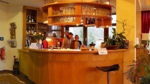 Un mostrador de recepción de madera con una vitrina de cristal, un extintor y una zona de bar con taburetes.