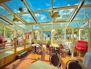 A restaurant with a glass ceiling, outdoor seating, and red chairs.