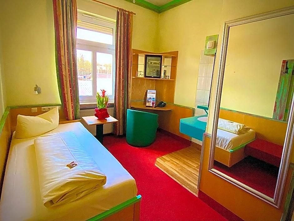 Habitación de hotel con cama, escritorio, silla, espejo y ventana con cortinas.