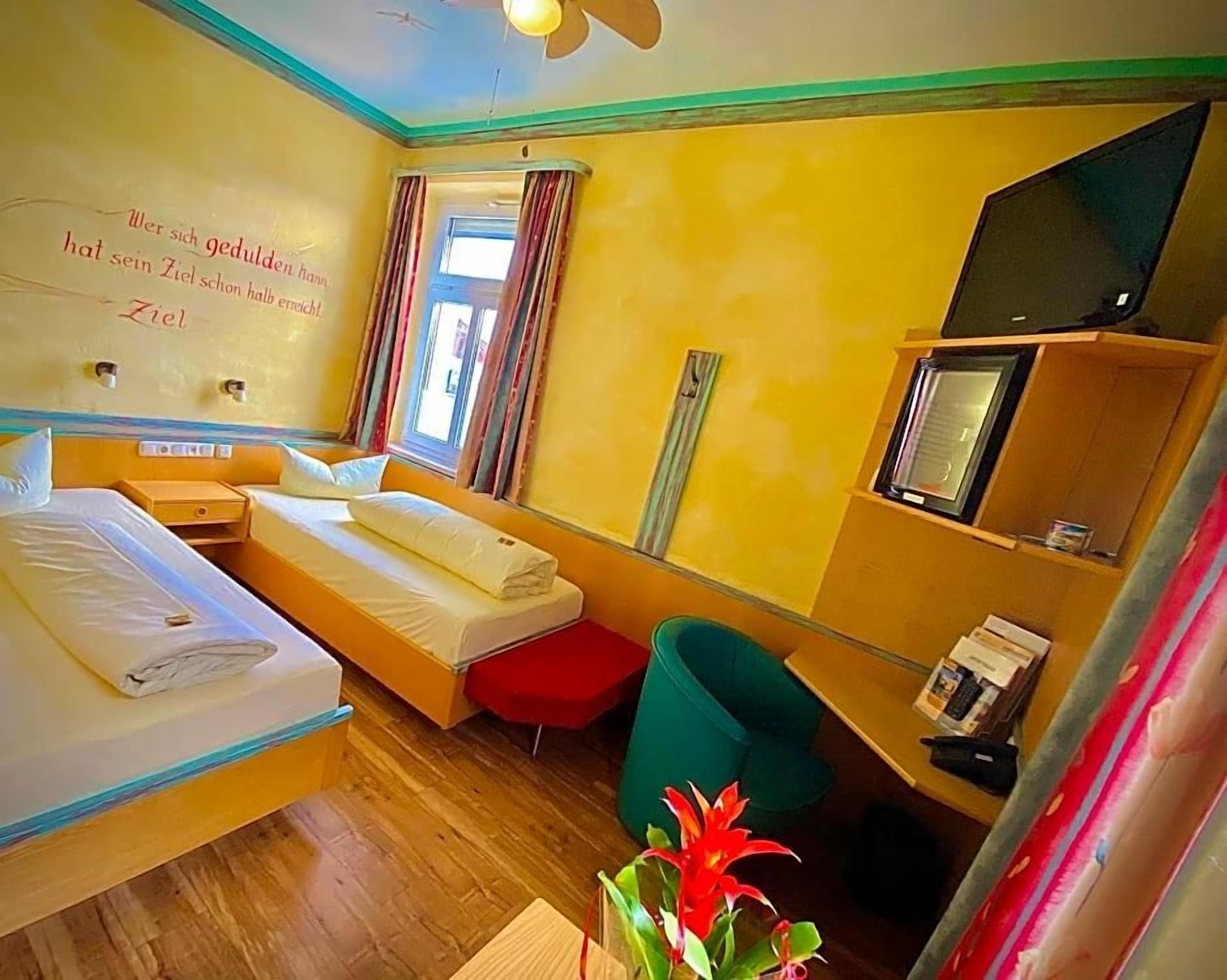 A hotel room with a bed, a desk, a chair, a television, and a window with curtains.