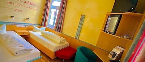 A hotel room with a bed, a desk, a chair, a television, and a window with curtains.
