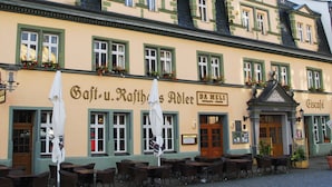 A historic building with a cafe and restaurant on the ground floor, featuring outdoor seating with umbrellas. - Hotel Adler (Rudolstadt)