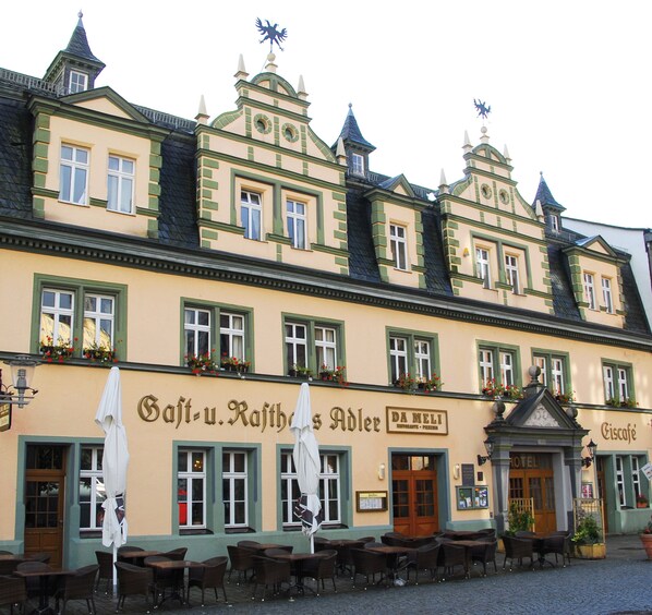 A historic building with a cafe and restaurant on the ground floor, featuring outdoor seating with umbrellas. - Hotel Adler (Rudolstadt)