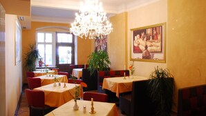 A dining area with tables, chairs, a chandelier, and artwork on the walls. - Hotel Adler (Rudolstadt)