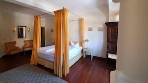A bedroom with a four-poster bed, a small bedside table with a lamp, a chair, and a piano. - Hotel Adler (Rudolstadt)