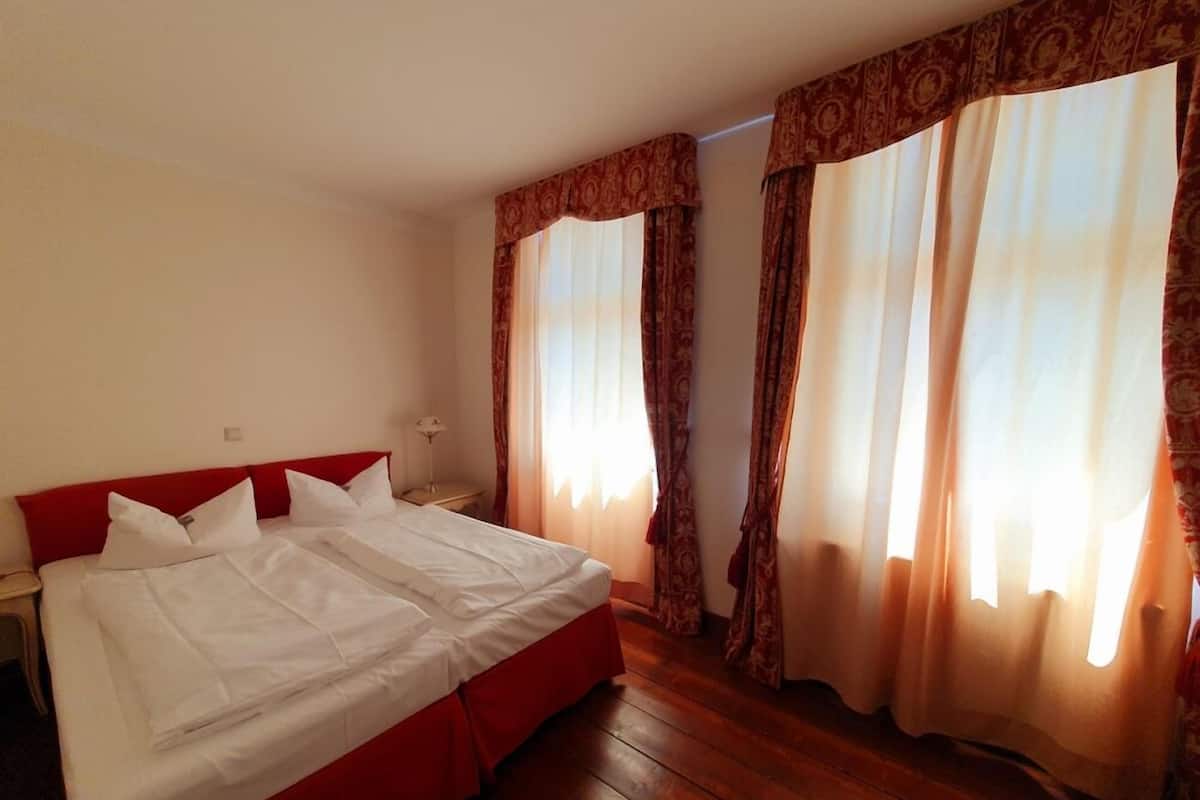 A double bed with a red headboard, a bedside table, and a nightstand.