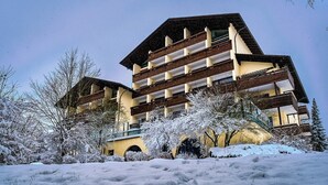 Un immeuble à étages doté d’une façade symétrique, de grandes fenêtres et surplombant un paysage enneigé.