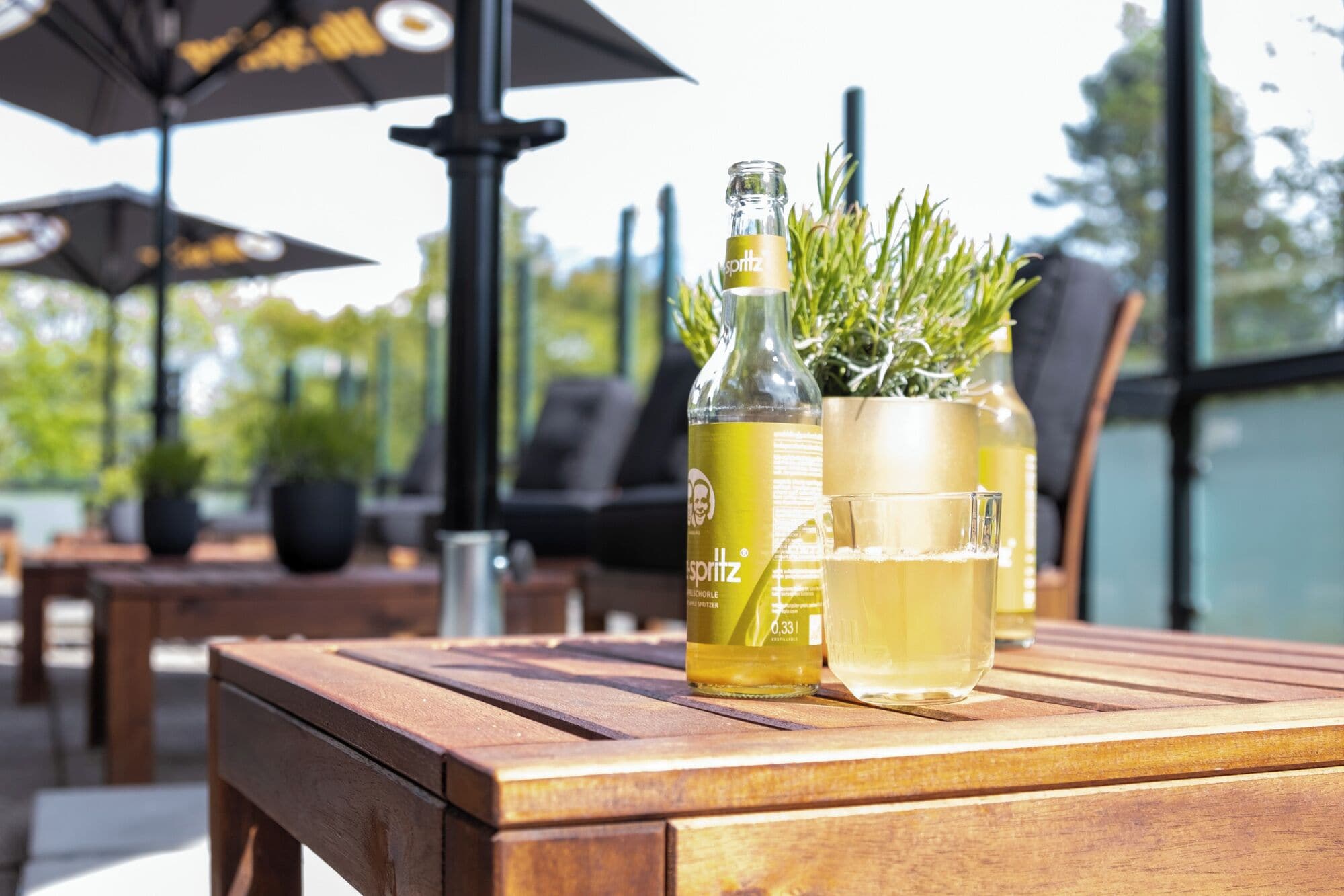 A wooden table with a bottle of Esprit, a glass, and a potted plant.