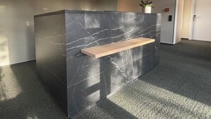 A reception desk with a marble finish, a wooden shelf, and two hanging pendant lights. - Hotel am Stadthaus (Neuenburg am Rhein)