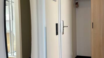 Un couloir avec une porte blanche, une carte encadrée accrochée au mur et une porte en bois sur la droite.