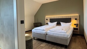 A modern bedroom with a double bed, a bedside table with a lamp, and a wooden floor. - Hotel am Stadthaus (Neuenburg am Rhein)
