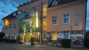 A hotel with a large illuminated sign, multiple windows, and a mural on the facade. - Hotel am Stadthaus (Neuenburg am Rhein)