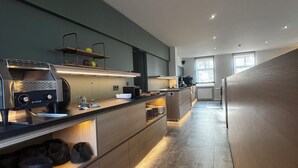 A modern kitchen with a long countertop, built-in appliances, and a wooden floor. - Hotel am Stadthaus (Neuenburg am Rhein)