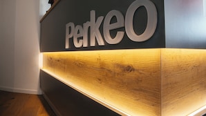 A reception desk with a wooden finish and a sign that reads "PerkeO".