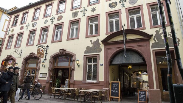 A building with multiple windows, a central entrance, and outdoor seating.
