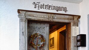 A hotel entrance with a wrought iron gate, a wooden door, and a sign reading "Hoteleingang".