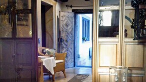 A room with a wooden door, a dining area with a table and chairs, and a large glass vase on the floor.