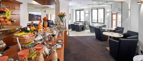 A hotel lobby with a buffet area featuring various food items and a seating area with modern furniture.