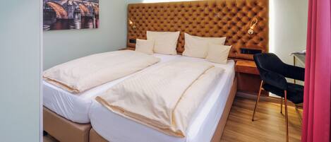 A double bed with a tufted headboard, a bedside table with a lamp, and a chair.
