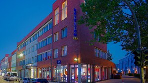 A multi-story hotel with a prominent 'HOTEL' sign, a parking sign, and a visible entrance with glass doors. - Hoteltow (Teltow)