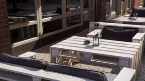 Outdoor seating with tables and benches, some with cushions. - Hoteltow (Teltow)