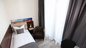 Ein Hotelzimmer mit Bett, Sessel, Nachttisch und einem Bild an der Wand.