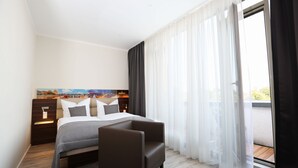 A modern hotel room with a bed, a chair, a nightstand, and a painting on the wall. - Hoteltow (Teltow)