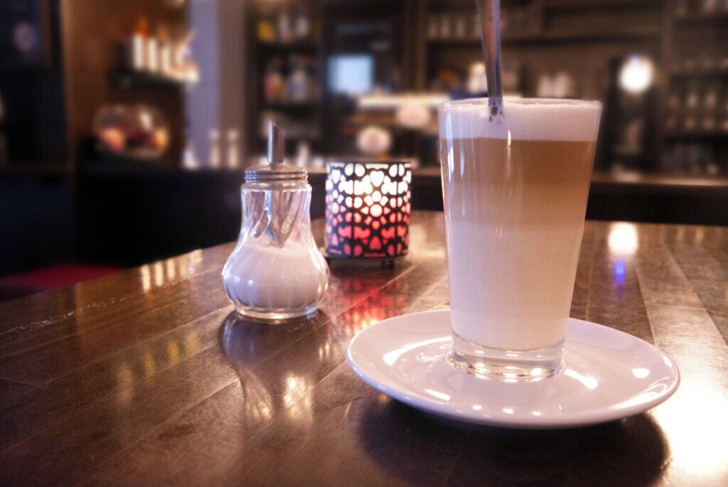 Et glas med et lagdelt drikkemøde på en hvid tallerken, med et stearinlys i baggrunden.