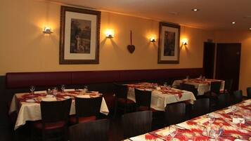 Ein Restaurant mit mehreren gedeckten Tischen, jeweils mit Tischdecke und Weingläsern.