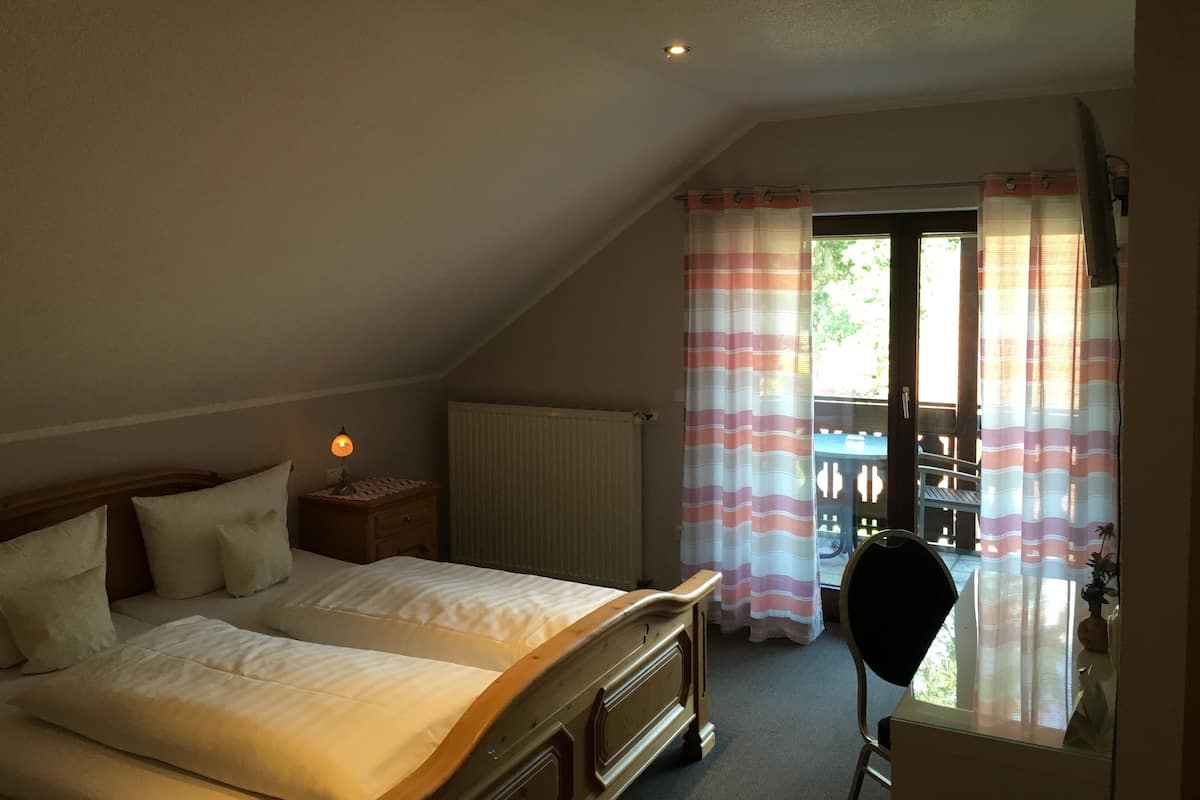 Une chambre à coucher avec un lit, une lampe de chevet et une vue sur l’extérieur par une fenêtre munie de rideaux.