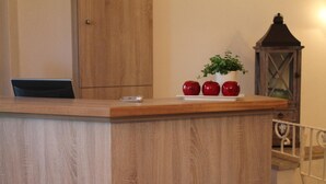 A wooden reception desk with a laptop, a smartphone, and a potted plant with apples. - Landhaus Pension Göke (Hoevelhof)