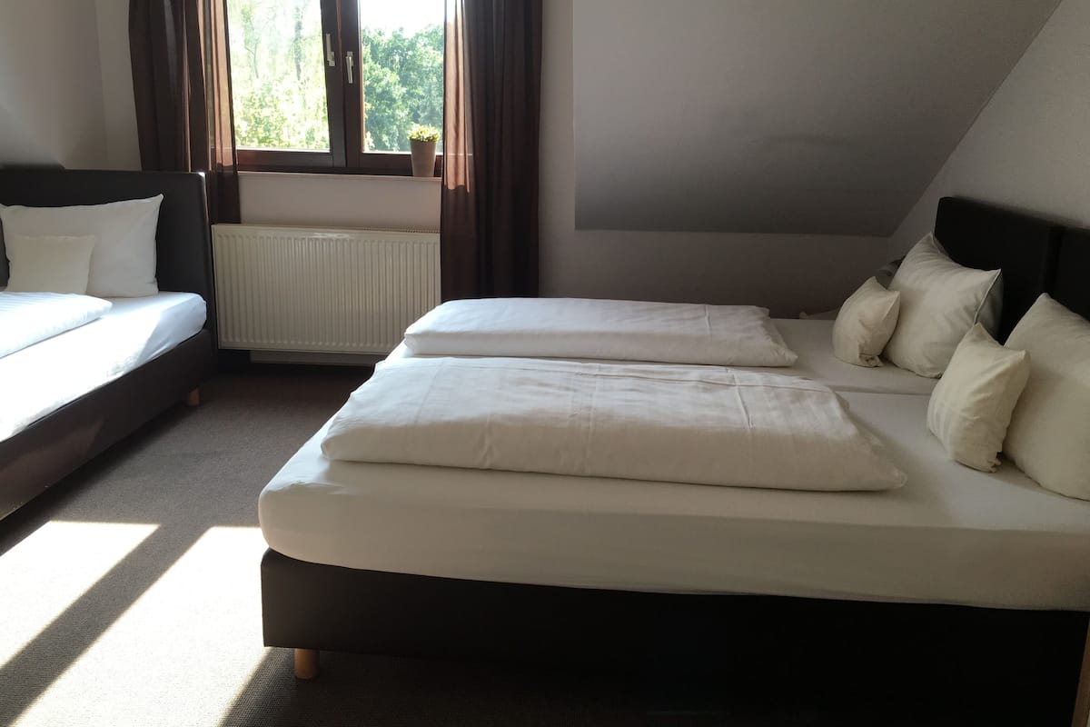 Une chambre avec deux lits, un radiateur et une fenêtre avec des rideaux.