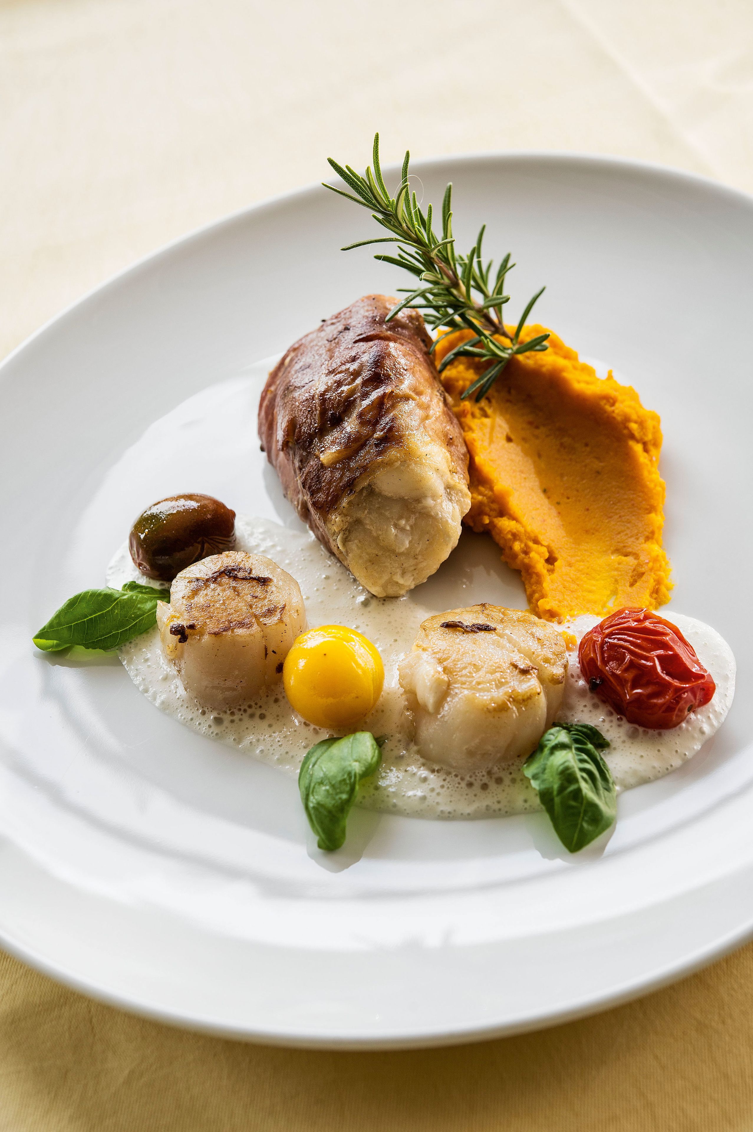 Ein weißer Teller mit Fleisch, geröstetem Gemüse und einer Soßenportion.