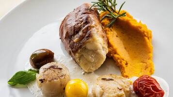 Ein weißer Teller mit Fleisch, geröstetem Gemüse und einer Soßenportion.
