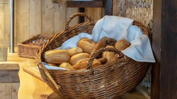 A wicker basket filled with various breads on a wooden table.