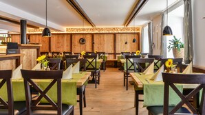 Un restaurante con paredes de madera, sillas tapizadas en verde y mesas decoradas con girasoles.