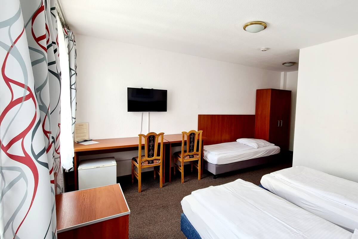 Een hotelkamer met een bed, een bureau, twee stoelen, een televisie en een kledingkast.