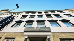 Un edificio con un cartel que dice "HOTEL ZENTRUM HANNOVER" y una señal negra con letras blancas encima.
