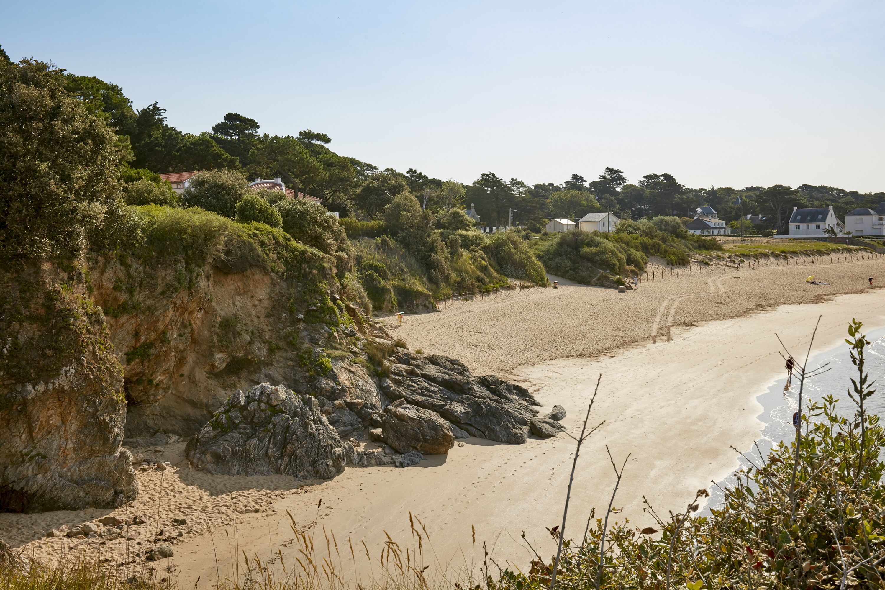 A coastal beach with rocky cliffs and a sandy shore.