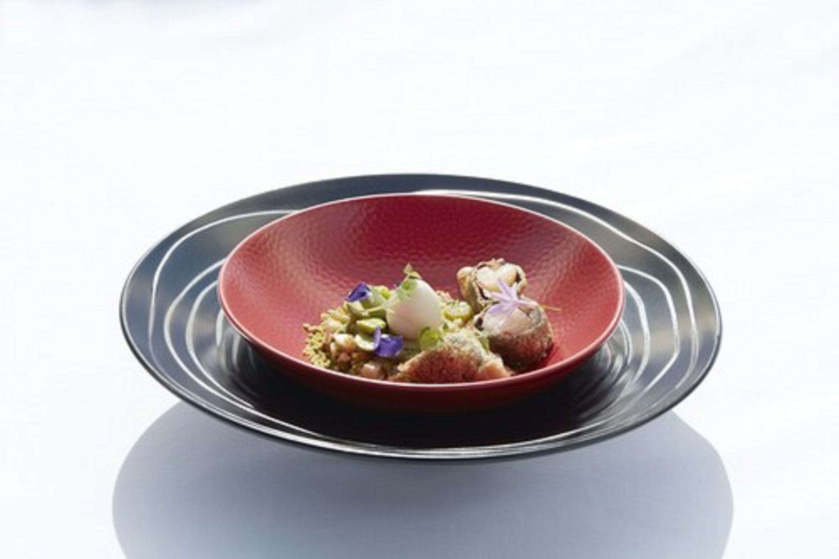 A red plate with a dish on a reflective surface.