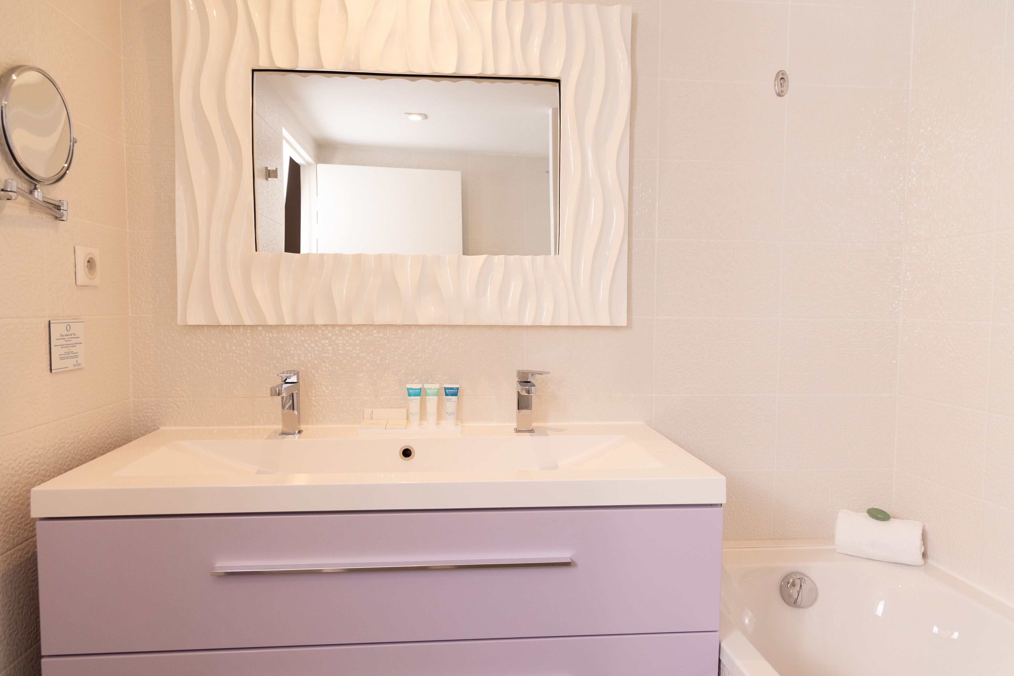 Une salle de bain avec un meuble-lavabo blanc, un miroir, une baignoire et une serviette.