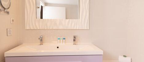Une salle de bain avec un meuble-lavabo blanc, un miroir, une baignoire et une serviette.