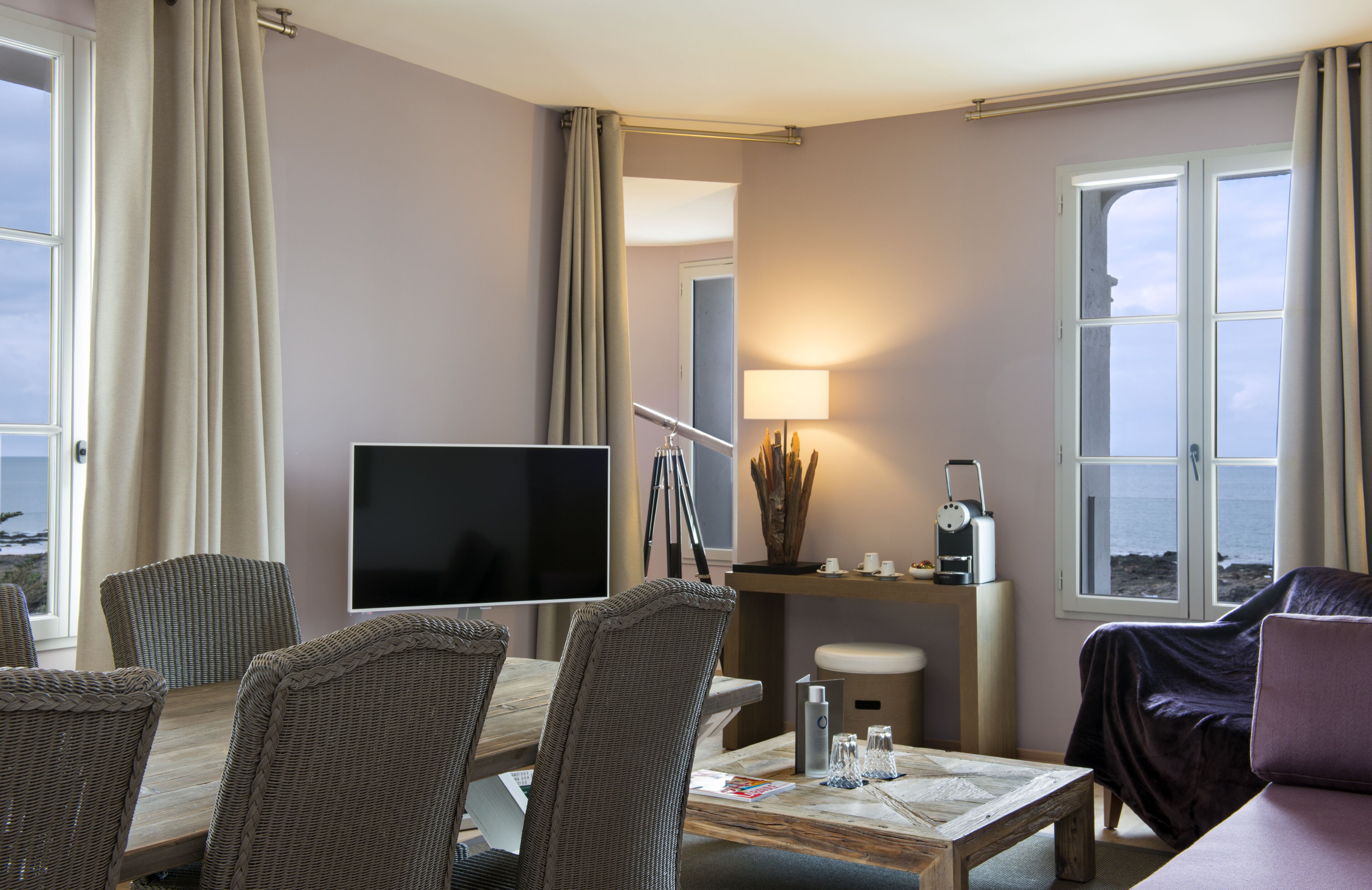 Ein Hotelzimmer mit Essbereich, Fernseher, Lampe und Meerblick.