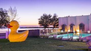 Guests can enjoy a serene outdoor setting with a large duck sculpture, pool, and beautifully manicured lawn.