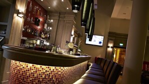 Een bar met een betegelde toonbank, barstoelen en een televisiescherm.