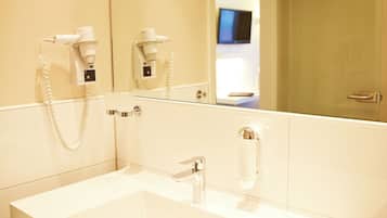 A modern bathroom with a large mirror, a white sink, and a hairdryer mounted on the wall.